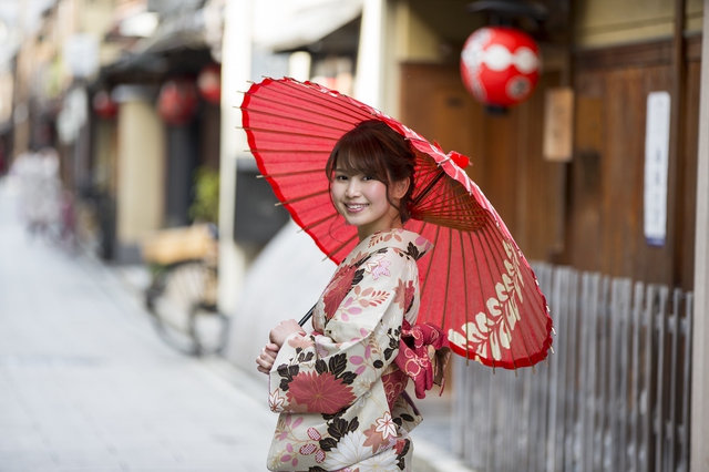 紅い傘をさして着物姿で花見小路を歩く女性